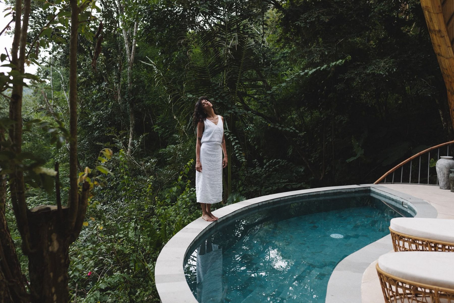 Woman in white dress overlooking the jungle from a private villa pool